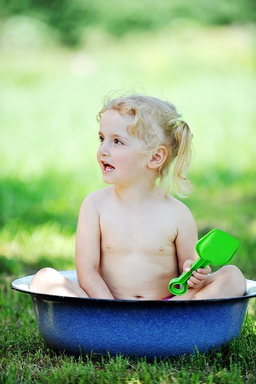 little girl sits in  basin with water. Hot summer day