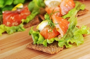 pieces of  salmon with lemon  lettuce   and small loafs