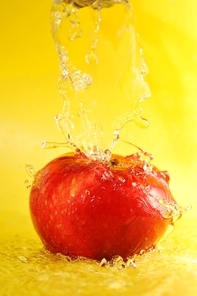 apple and water splashes on  yellow close up