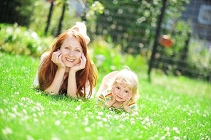 Beautiful young mother with her  daughter lie on grass . summer.