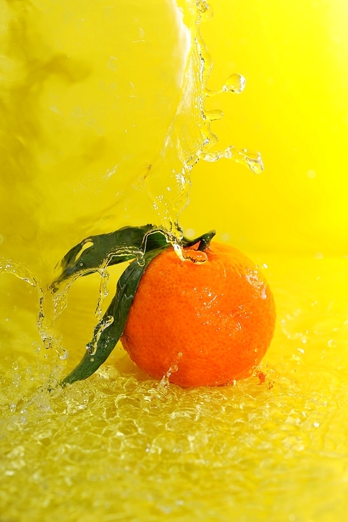 tangerine and water splashes on yellow close up