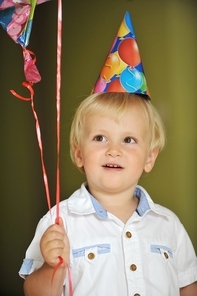 little boy with birthday hat play with balloons