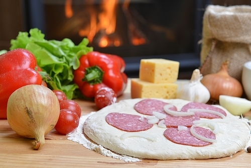 delicious pizza dough|spices and vegetables on wooden table