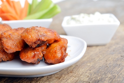 chicken wings with celery and carrot on wooden background