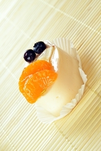 Small  cake  with white icing and tangerines on bamboo table cloth