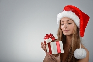 Beautiful young woman in santa claus hat holding gift box
