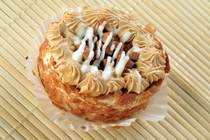 Delicious caramel's  cupcake with white icing on bamboo table cloth