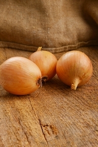 Open jute sack with ripe onions  on wooden board