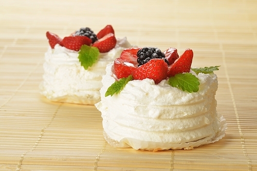 tasty cakes  with white icing and strawberries on bamboo table cloth
