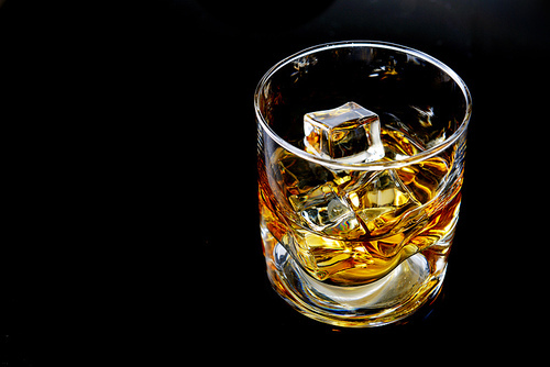 Whiskey with ice in simple glass on  black background