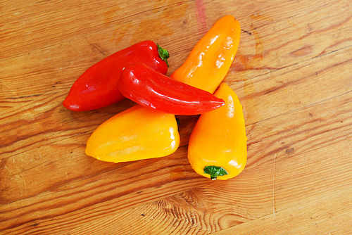 red and yellow  ripe peppers lies on wooden cutting board