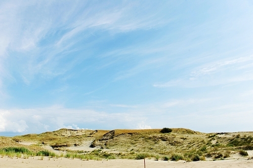 White clouds on blue sky over dunes