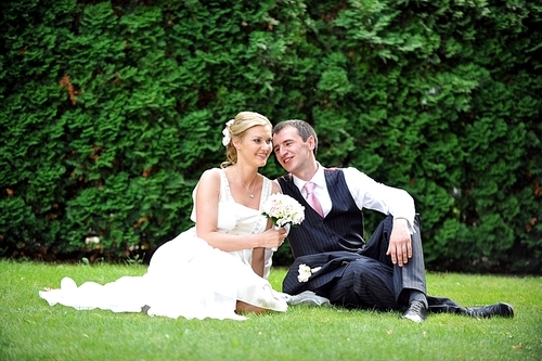 newly-married couple  on green grass in field