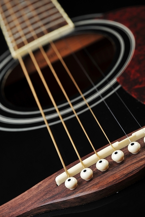 Detail of an acoustic black guitar with the strings and the sound hole