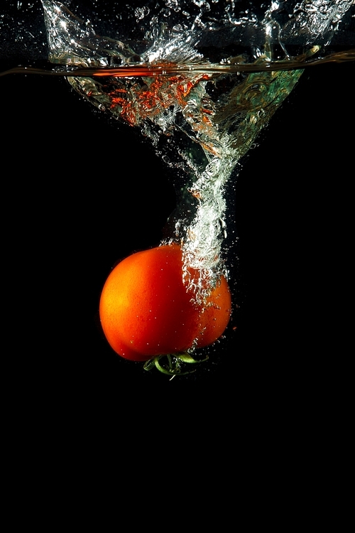 fresh tomato uder water on black background