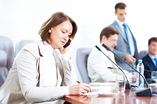 Image of businesswoman at business meeting with three businessmen in background