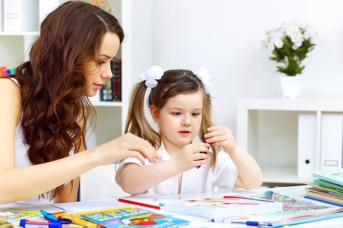 Young mother with little daughter studying at home