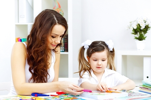 Young mother with little daughter studying at home