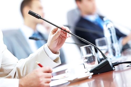 Image of businessman's hands holding microphone at conference