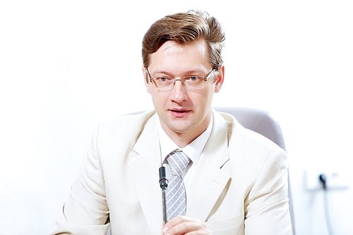 Image of young businessman sitting at table at business meeting