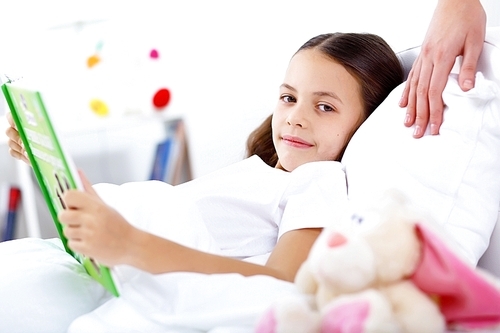 Portrait of girl with a book in bed at home