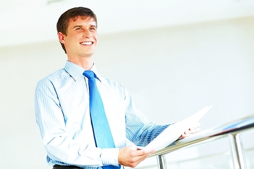 Portrait of happy smiling young businessman|standing in office