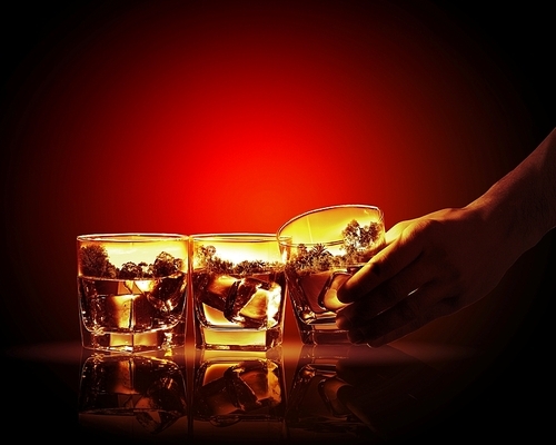 Hand holding one of three glasses of whiskey with nature illustration in