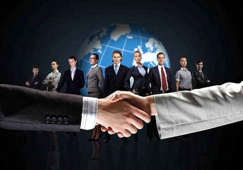 business handshake against black background and standing businesspeople