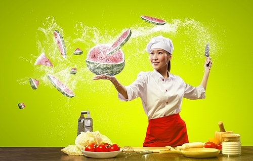 Asian female cook with knife cutting fruits and vegetables in air