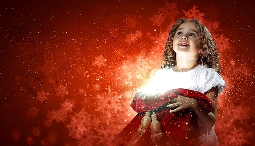 A cute young girl holding a christmas gift|dark background with christmas light bokeh