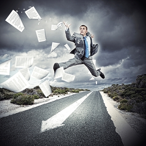 Young businessman in suit running on the road