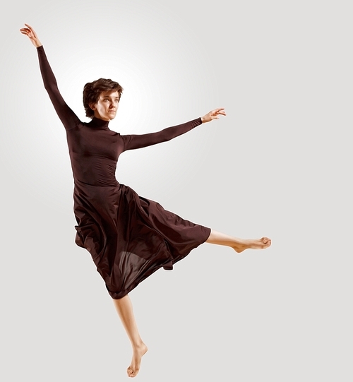 Girl dancing in a dark dress with a gray background. isolate