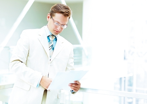 Young businessman in suit working in bright office|standing