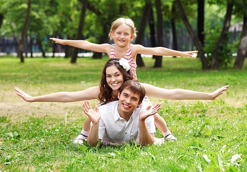 Young Family Outdoors on the grass in Park in summer