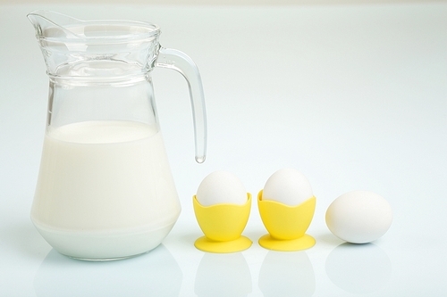 Milk in a glass jar and eggs on the table