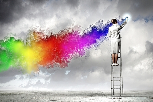 Young woman standing on ladder drawing splashes with finger