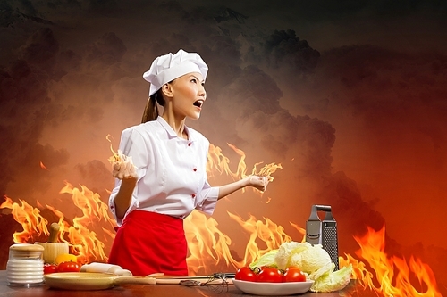 Asian female cook in anger against color background with shine effects