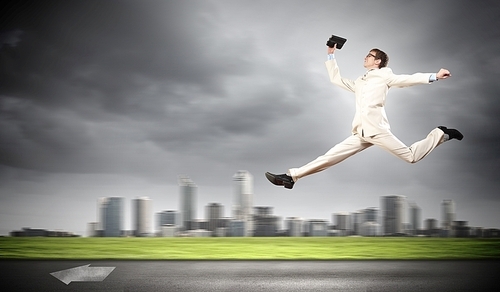 Young businessman in suit running on the road