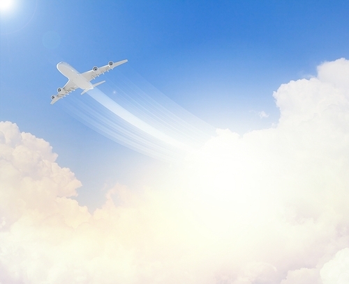 Image of flying airplane in clear sky with sun at background