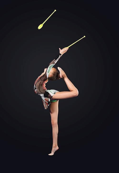Young cute woman in gymnast suit show athletic skill on black background