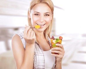 Portrait of happy woman eating tasty fruit salad at home, healthy nutrition, dieting snack, enjoying sweet organic food