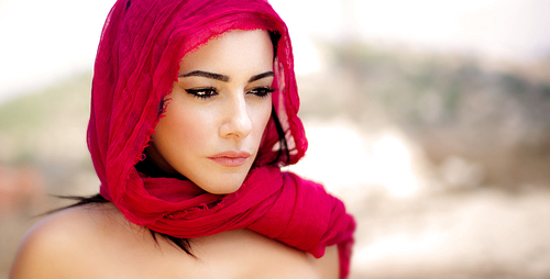 Beautiful arabic woman wearing red scarf, stylish female portrait over soft natural background with copy space