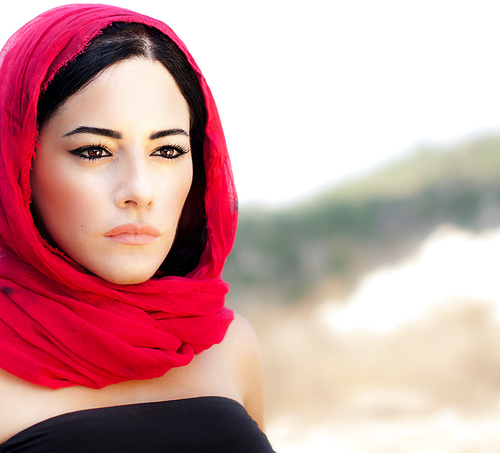 Beautiful arabic woman wearing red scarf, traditional muslim clothes, latest fashion design, stylish female portrait over soft natural background with copy space