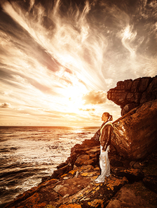 Traveler girl on the cliff, beautiful sunset on seascape, photographer woman, active lifestyle, expedition to mountains, travel concept