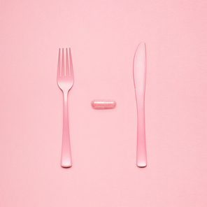 Still life of fork and knife at a lunchtime with a pill served.