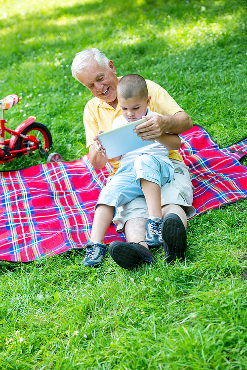 grandfather and child using tablet computer in park