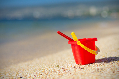 Baby bucket on sand at sea coast