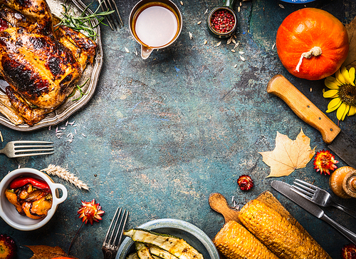 roasted whole chicken or turkey with sauce and grilled autumn : corn,pumpkin ,paprika on dark rustic background, top view, frame. thanksgiving day food concept