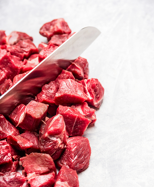 raw  cubes chopped meat for goulash or stew with knife, top view