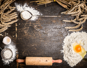 Baking background with bake tools, flour,egg and rolling pin on rustic wooden background, top view